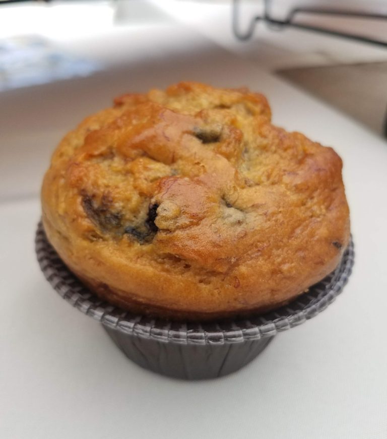 Freshly baked banana bread muffin topped with a golden crust and blueberries.