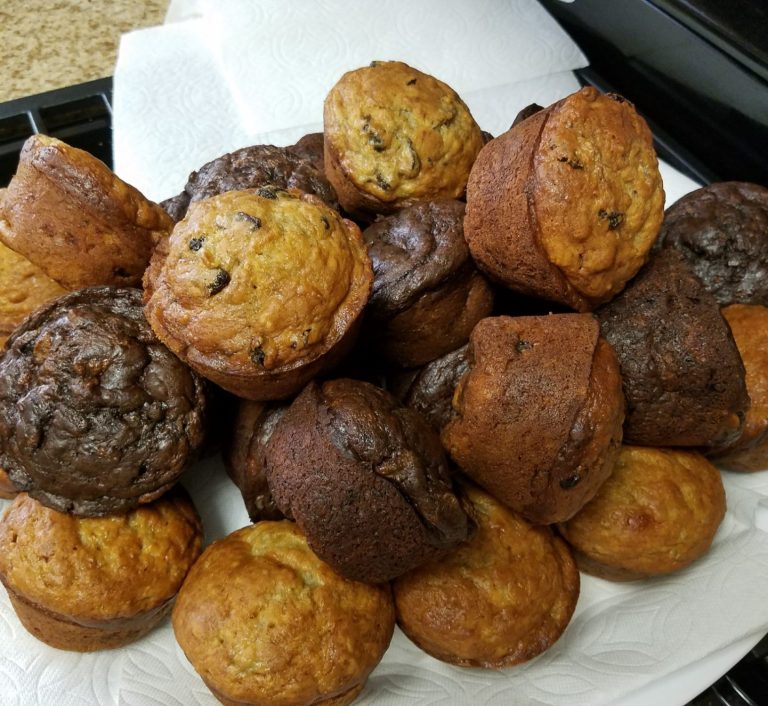 A pile of assorted banana bread muffins, including chocolate and blueberry varieties.